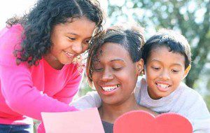 First time home buyer mother wit her two young children smiling as they look at their mortgage document.